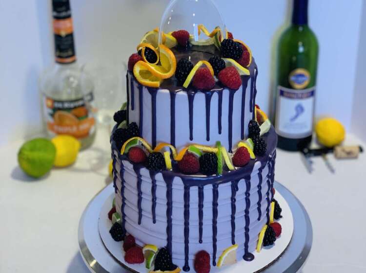 Tiered Berry Sangria cake - topped with fresh fruit, a purple drip, and a wine glass
