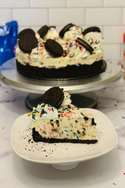 No-Bake Oreo Confetti Cheesecake: cut No-Bake Oreo Confetti Cheesecake: slice cut on a plate in front of cheesecake
