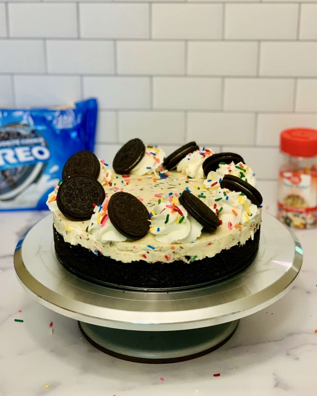No-Bake Oreo Confetti Cheesecake, Oreo crust decorated with whipped cream swirls and Oreo cookies