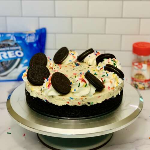 No-Bake Oreo Confetti Cheesecake, Oreo crust decorated with whipped cream swirls and Oreo cookies